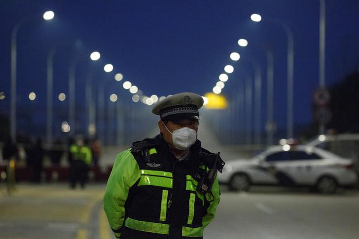 A police officer stands at a roadblock at a bridge crossing the Yangtze River to Hubei province in Jiujiang, Jiangxi province, China, as the country is hit by an outbreak of a new coronavirus, January 30, 2020. REUTERS/Thomas Peter