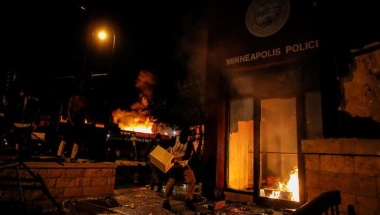 A protester sets fire to the entrance of a police station as demonstrations continue after a white police officer was caught on a bystander's video pressing his knee into the neck of African-American man George Floyd, who later died at a hospital, in Minneapolis, Minnesota, U.S., May 28, 2020. REUTERS/Carlos Barria